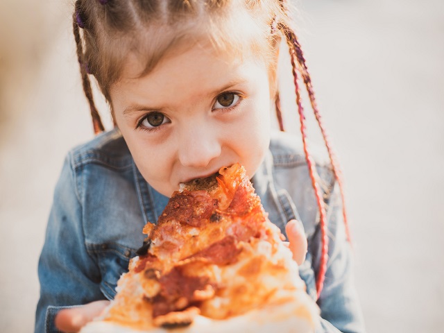 une petite fille mangeant une tranche de pizza
