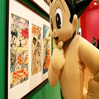 Mascotte Astro Boy devant planches de BD exposées