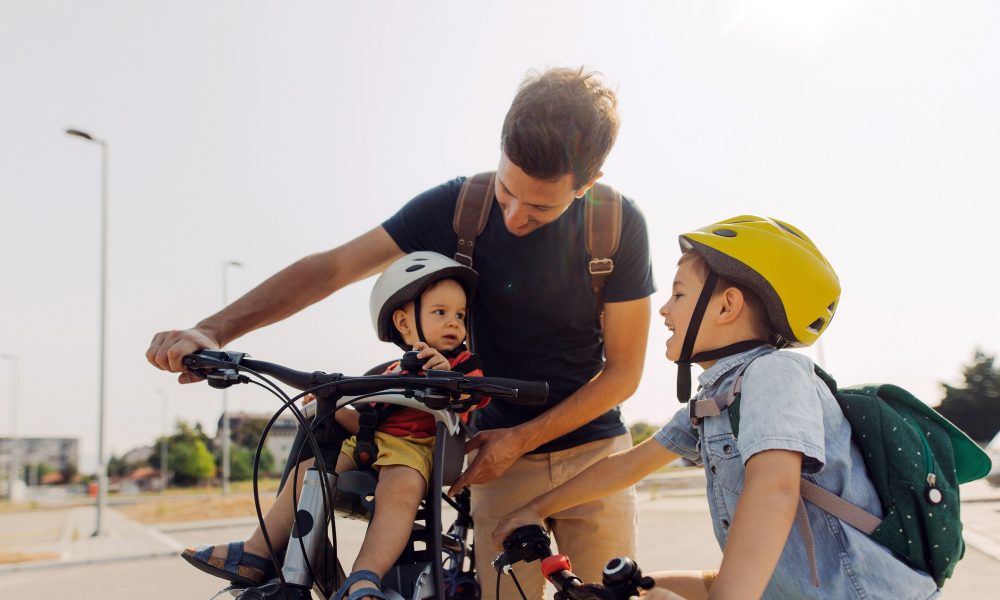 Un père et ses deux enfants se rendant à l’école à vélo.