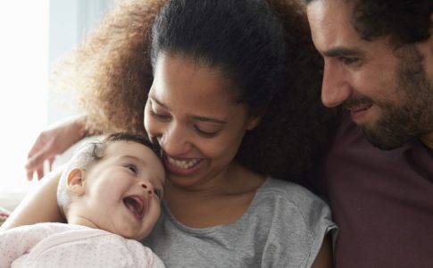 Un petit bébé épanoui dans les bras de ses parents comblés de bonheur