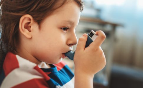 Un cas d’asthme chez l’enfant : un petit garçon en train d’inhaler de la ventoline à pleine bouchée.