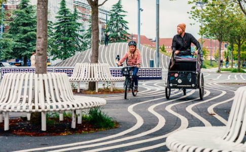 Une piste cyclable de vélo à Copenhague arpentée par une jeune cycliste et son père conduisant un vélo cargo.