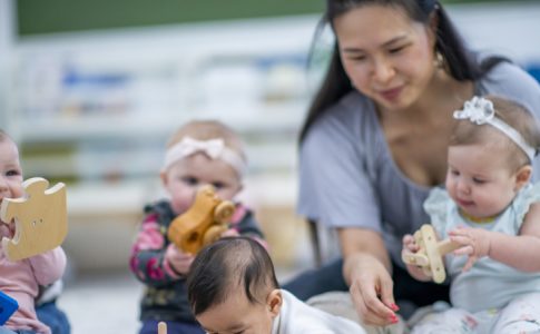 Adeptes de la tendance scrunchy moms ou pas, voici une éducatrice dans une crèche avec de petits bébés autour d’elle.