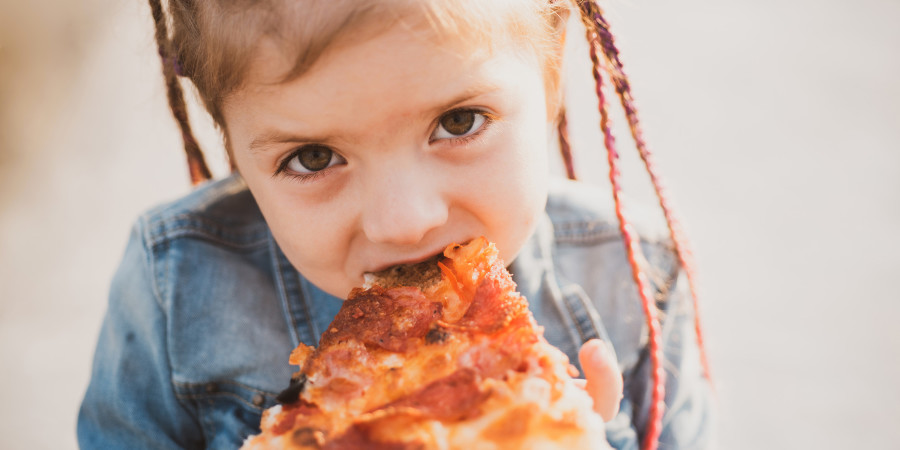 Une fillette dévorant une pizza surgelée, un des aliments malsains pour enfants les plus plébiscités.