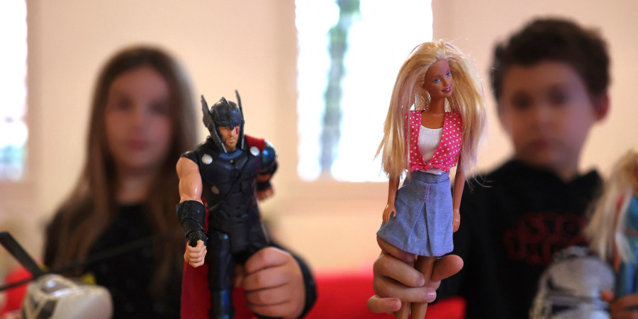 Un garçon tenant une poupée et une fille tenant une figurine de héros pour mettre en avant le concept de jouets non-genrés.