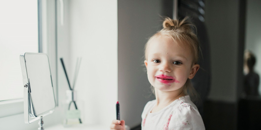 Une petite fille avec les lèvres peinturlurées de stick à lèvres, un produit avec une potentielle exposition aux substances toxiques.