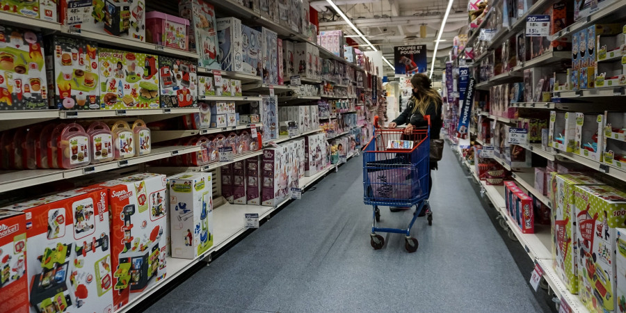 Une femme avec son caddy dans une enseigne de distribution proposant un large choix de jouets écoresponsables.