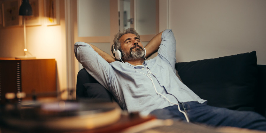 Un homme en train de se détendre sur son sofa en écoutant des podcasts pour s’endormir.