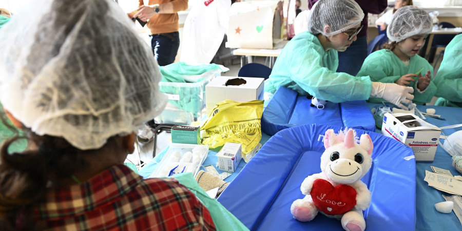 Une peluche licorne assise sur une table à l’hôpital des nounours, entourée de jeunes enfants en pleine découverte médicale
