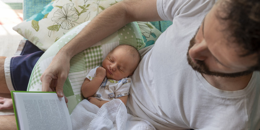 Bénéficiant d’une extension congé paternité, un père en train de s’occuper de son bébé endormi.