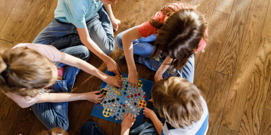 Cinq enfants assis en rond, en train de jouer aux jeux de société.