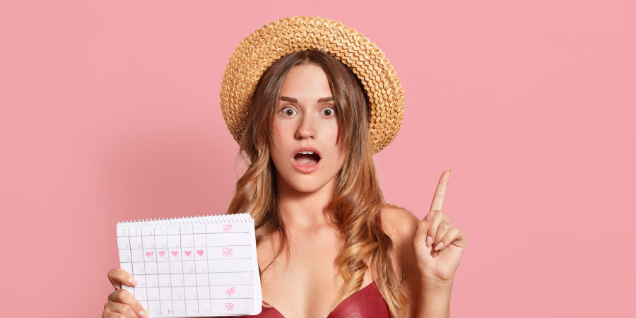Une jeune femme portant un maillot de bain menstruel et tenant à la main un calendrier périodique.