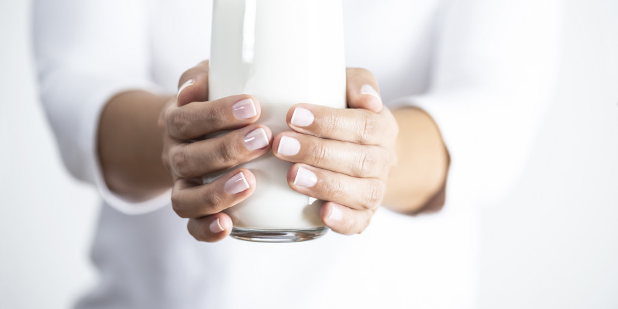 Une femme tenant de ses deux mains un verre contenant une catégorie de laits végétaux