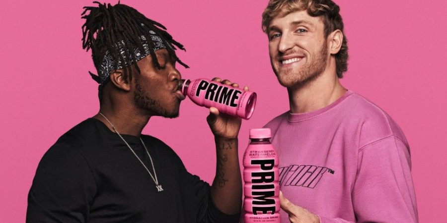 Deux hommes en train de faire la promotion de la boisson Prime Energy sur un fond rose.