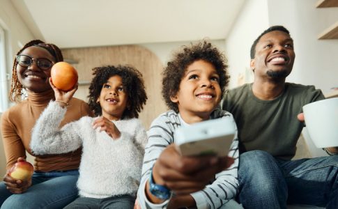 Une famille passant un moment devant la télé, avec les parents s’accommodant au choix de plateforme de streaming de leurs enfants.
