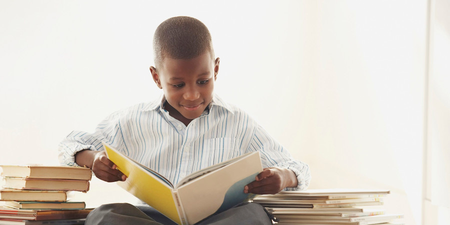 Un jeune garçon lisant des livres, un moyen d’améliorer ses notes à l’école tout comme les contenus audios.