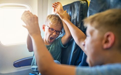 Deux garçons en train de se chamailler dans un avion, une des raisons justifiant la création d’une zone pour les voyageurs sans enfants.