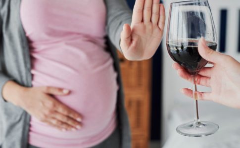 Une future maman refusant un verre de vin, consciente des risques de l’alcool pendant la grossesse.