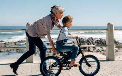 Une mamie active apprenant le vélo à sa petite fille, une grand-mère qui peut prétendre au congé grand-parental.