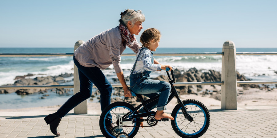 Une mamie active apprenant le vélo à sa petite fille, une grand-mère qui peut prétendre au congé grand-parental.