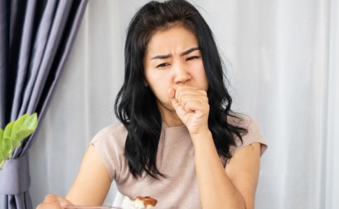 Une jeune femme en train de s’étouffer avec un aliment coincé dans la gorge.