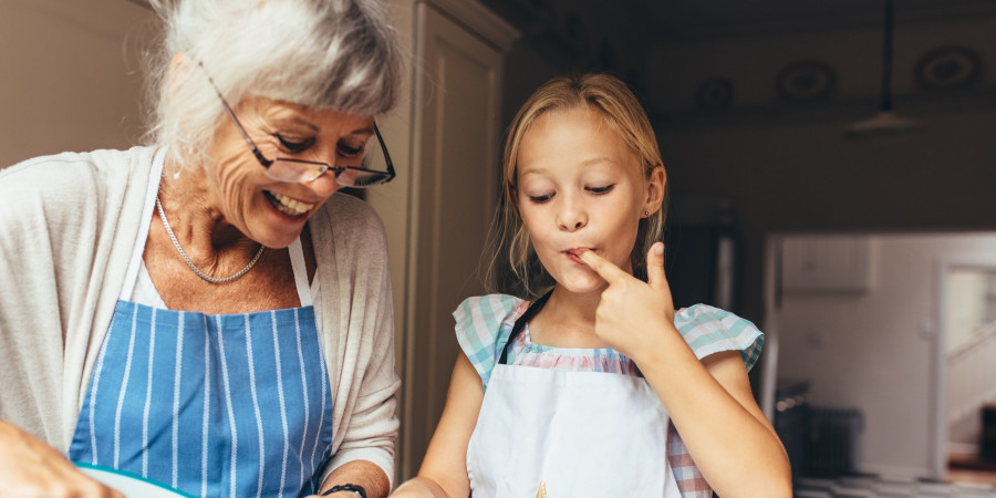 Une fillette et sa grand-mère en train de préparer des recettes familiales.