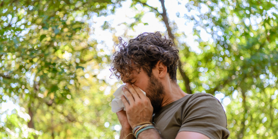Un homme en pleine nature en train de se moucher, une réponse à des épisodes d’allergies au pollen.