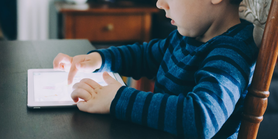 L’image d’un petit garçon obnubilé par sa tablette, illustrant la dépendance enfants aux écrans.