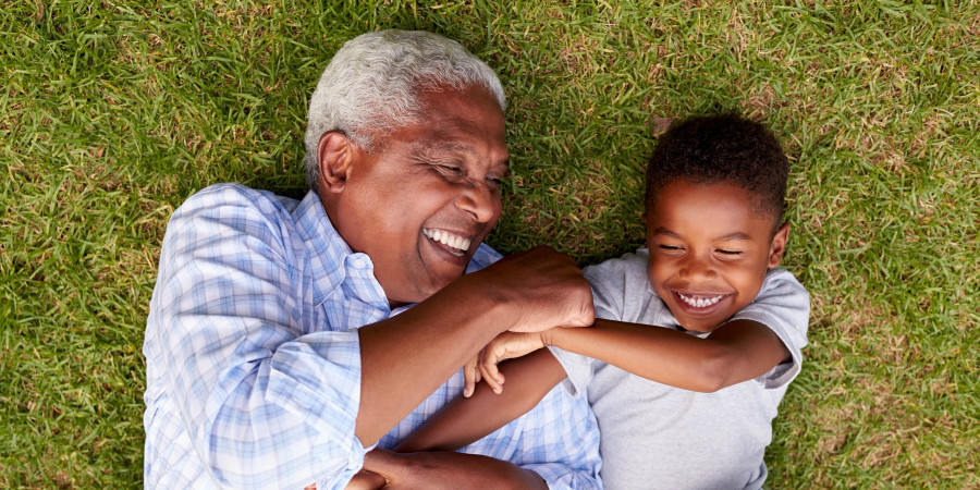 Un grand-père jouant avec son petit-fils, illustrant l’écart générationnel pouvant influencer le choix de prénoms enfants.