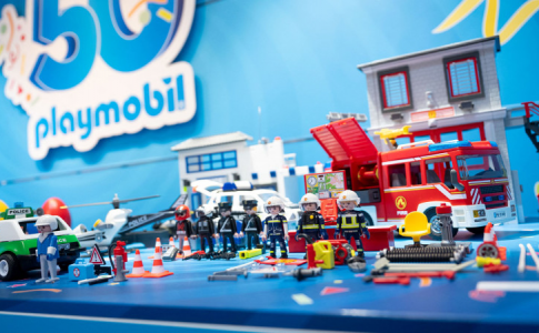 Le logo des 50 ans de Playmobil avec une table présentant quelques-unes de ses figurines.