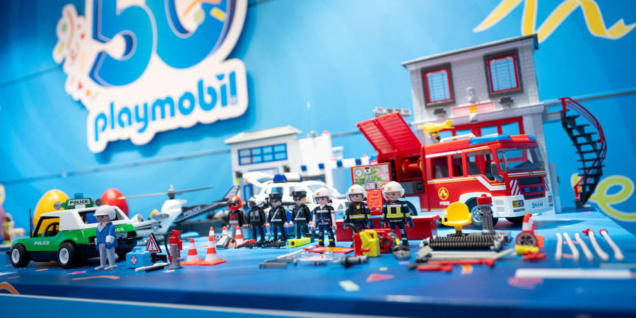 Le logo des 50 ans de Playmobil avec une table présentant quelques-unes de ses figurines.
