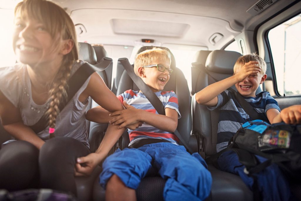 Trois enfants assis a l’arriere d’une voiture