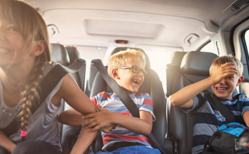 Une famille avec trois enfants partant pour les vacances de printemps en voiture.