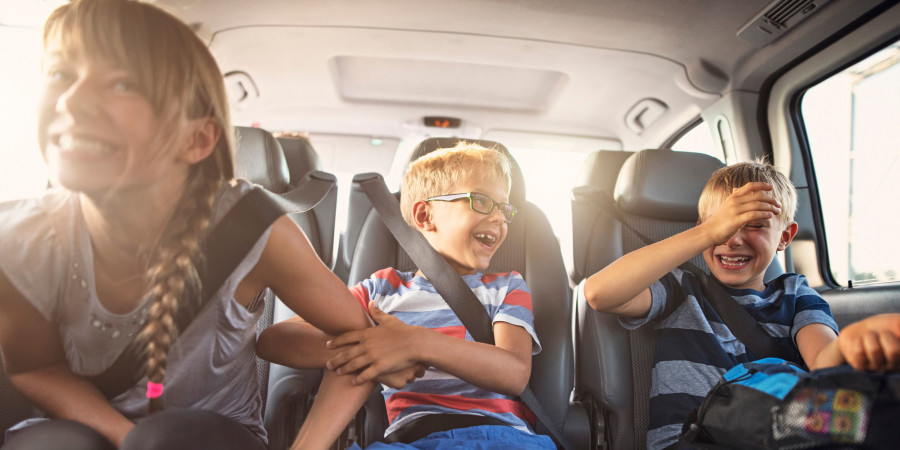 Une famille avec trois enfants partant pour les vacances de printemps en voiture.