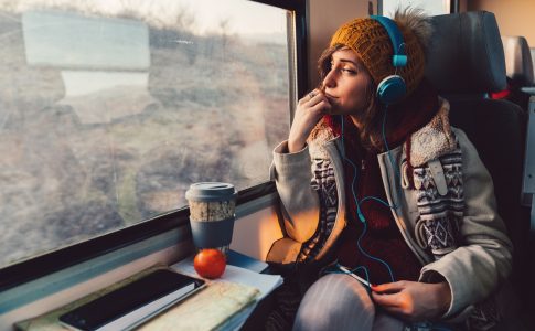 Une jeune femme dans le train ecoutant des contenus audio avec un casque pour se divertir