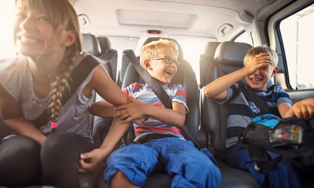 Ecrans route vacances : trois enfants assis a l’arriere d’une voiture