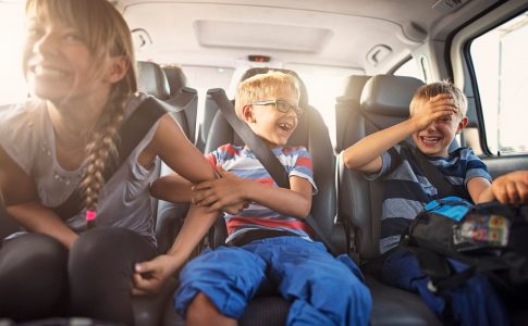 Ecrans route vacances : trois enfants assis a l’arriere d’une voiture