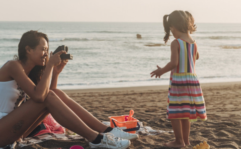 Une mère et sa fille à la plage, en train de prendre des photos de vacances.