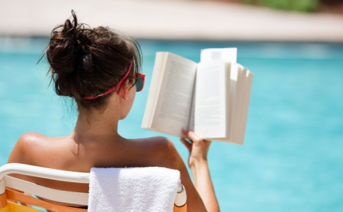 Une femme au bord de la piscine, figurant parmi les Français qui aiment lire en vacances.