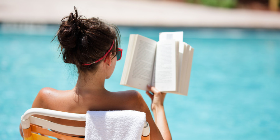 Une femme au bord de la piscine, figurant parmi les Français qui aiment lire en vacances.