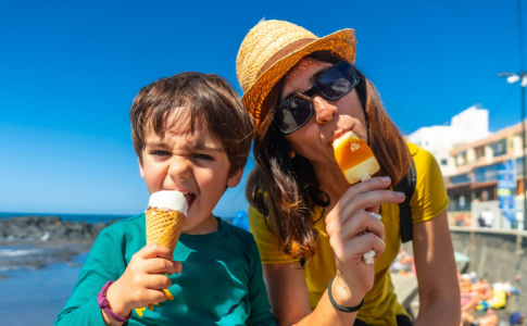 Une mère et son enfant à la plage, mangeant des glaces, un incontournable du budget alimentation durant les vacances.