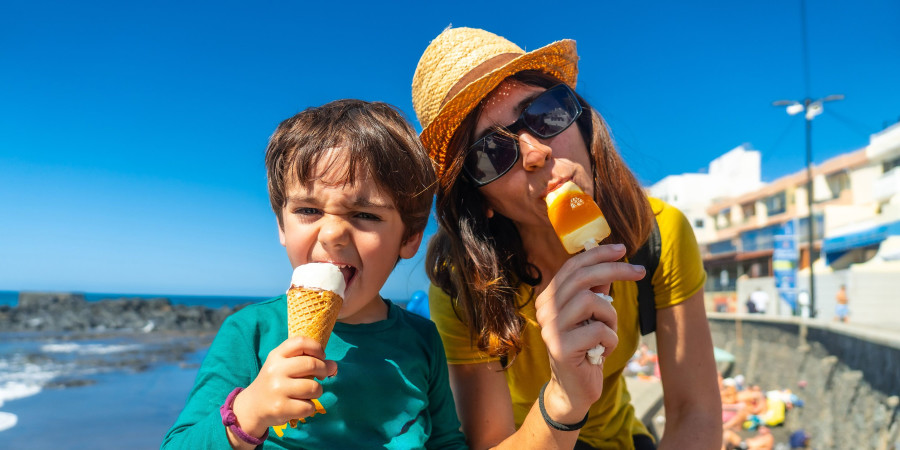 Une mère et son enfant à la plage, mangeant des glaces, un incontournable du budget alimentation durant les vacances.