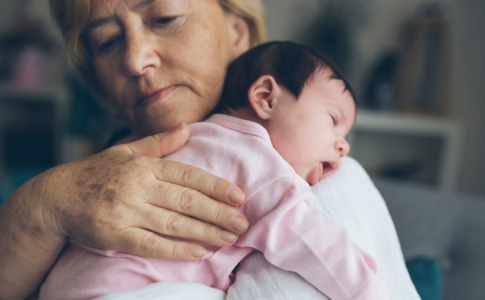 Une grand-mère berçant sa petite-fille, bénéficiant des nouveaux avantages du congé parental en Suède.