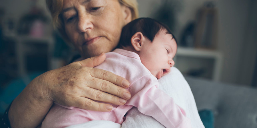 Une grand-mère berçant sa petite-fille, bénéficiant des nouveaux avantages du congé parental en Suède.