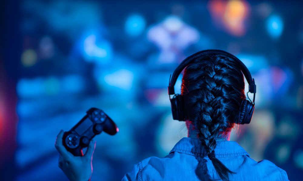 Une jeune fille concentrée joue un jeu vidéo sur son écran de télévision, immergée dans l'univers virtuel du jeu