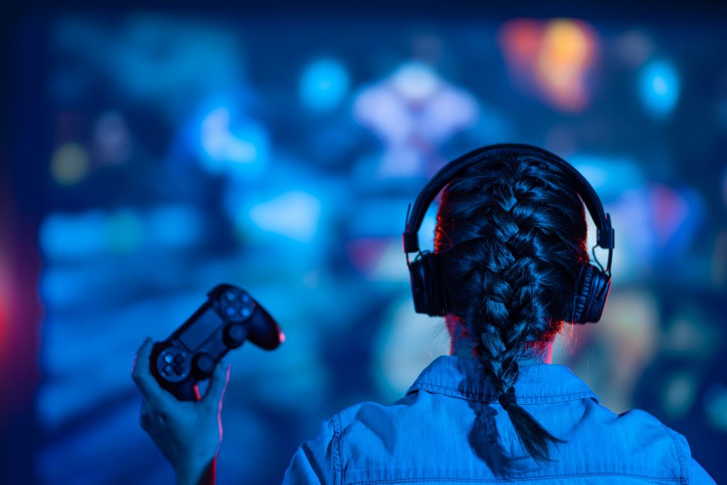 Une jeune fille concentrée joue un jeu vidéo sur son écran de télévision, immergée dans l'univers virtuel du jeu