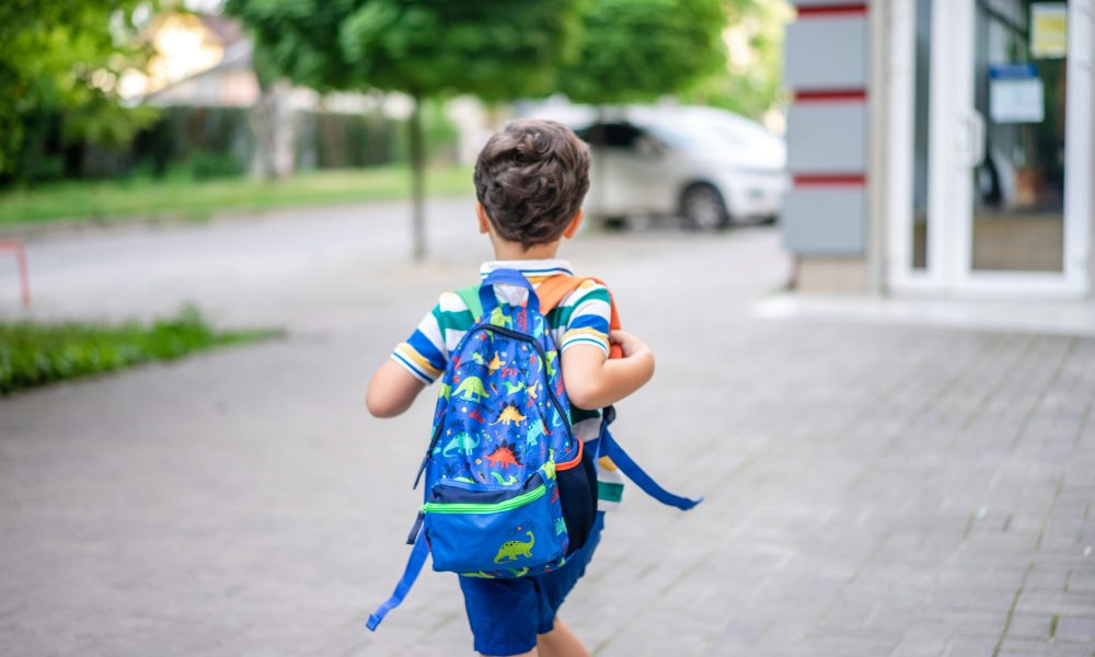 Un garçon tout heureux d’assister à son premier jour d’école, bien équipé grâce aux aides pour la rentrée scolaire.