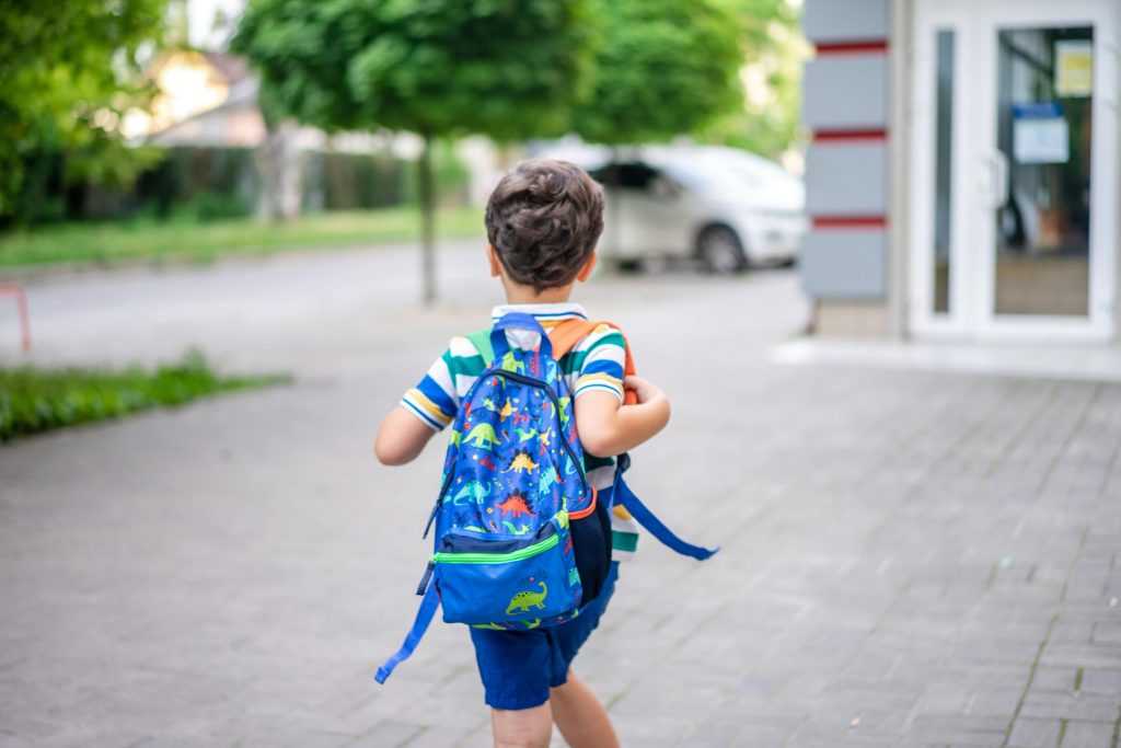 Un garçon tout heureux d’assister à son premier jour d’école, bien équipé grâce aux aides pour la rentrée scolaire.