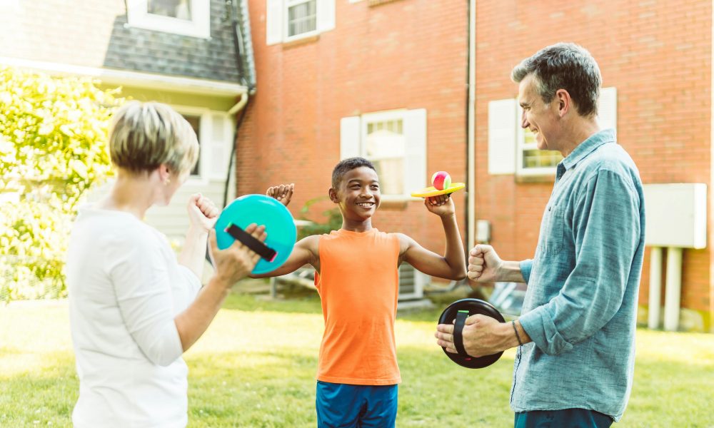 Un jeune garçon adopté, jouant allègrement dans le jardin avec ses nouveaux parents.