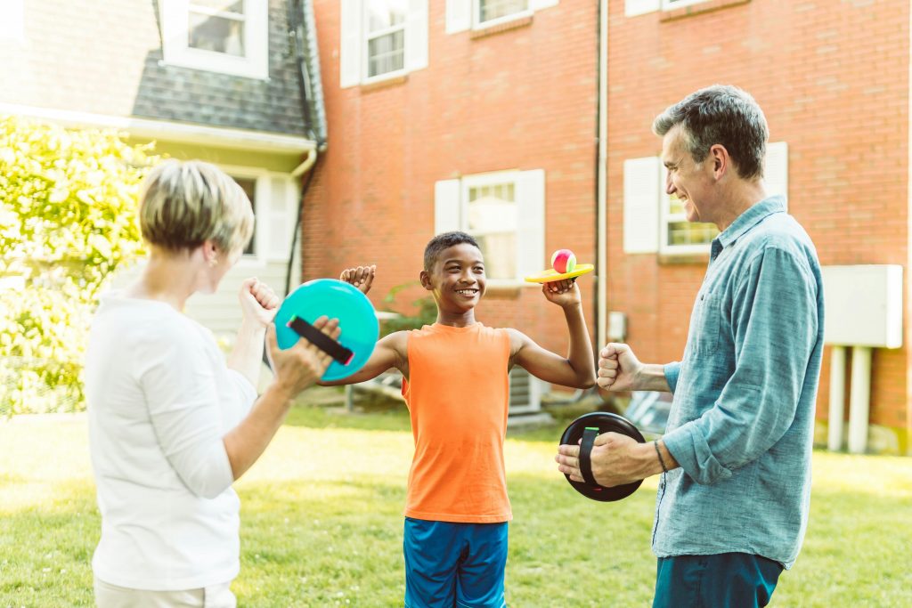 Un jeune garçon adopté, jouant allègrement dans le jardin avec ses nouveaux parents.